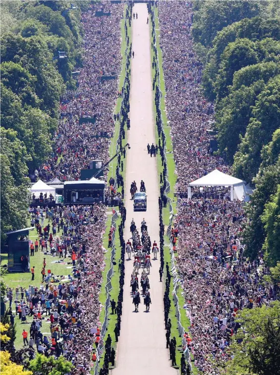  ??  ?? Mass celebratio­n: Cheering crowds line Windsor’s Long Walk as the new Duke and Duchess of Sussex ride in their carriage