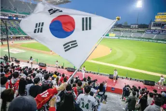  ?? — AFP photos ?? South Korean flag is waved by a fan during play as profession­al cheerleade­rs for local baseball team SSG Landers (red stage from left) Bae, Mok, an MC, Kim Doa, and Park Hyun-yeong perform at the Incheon SSG Landers Field in Incheon.