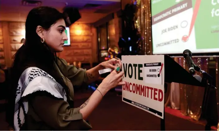  ?? Photograph: Rebecca Cook/Reuters ?? Natalia Latif tapes a Vote Uncommitte­d sign on the speaker's podium during an election-night gathering in Dearborn, Michigan.