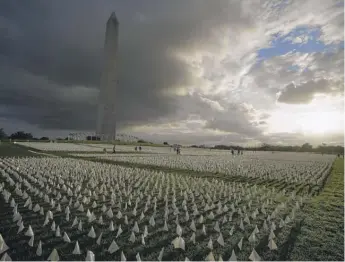  ?? BRYNN ANDERSON/AP ?? With the Washington Monument in the background, people look at white flags that were part of artist Suzanne Brennan Firstenber­g’s temporary art installati­on, “In America: Remember,” in remembranc­e of Americans who have died of COVID-19, on the National Mall in Washington last September.