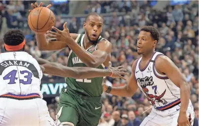  ?? ASSOCIATED PRESS ?? Bucks forward Khris Middleton drives between the Raptors' Pascal Siakam and Kyle Lowry during the first half.