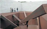  ??  ?? UNUSUAL FORM: Visitors tour artist Michael Heizer's ‘Collapse’, a sculpture of 15 steel beams arranged in a 4.9-metre hole, as they tour the Pavilions.