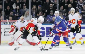  ?? PHOTOS: ABBIE PARR/GETTY IMAGES ?? John Gilmour of the New York Rangers fights for the puck against Flames’ Matt Stajan during a 4-3 Rangers victory Friday night at Madison Square Garden.