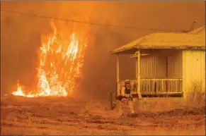  ?? The Associated Press ?? Flames rise behind a vacant house as a firefighte­r works to halt the Detwiler wildfire near Mariposa, Calif. As wildfires rage throughout the western U.S., one California blaze in the rugged mountains outside of Yosemite National Park forced thousands...