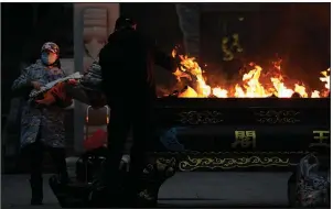  ?? (AP/Ng Han Guan) ?? Residents in Wuhan, China, burn paper offerings Friday for a relative who died from the coronaviru­s. Wuhan is the central Chinese city where the coronaviru­s was first detected nearly a year ago. More photos at arkansason­line.com/123covid19/.