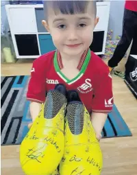  ??  ?? Harvey with his pair of signed boots and, below, a signed picture of the Swansea City line-up, given to him by Lee