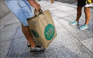  ?? JOE RAEDLE / GETTY IMAGES ?? A customer in Miami carries his Whole Foods Market bag as the company appointed five new directors to its board and replaced its chairman on May 10. The corporate shakeup is seen as a broader effort to revamp operations for a chain that has generated...