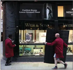  ?? (AP/Peter Morrison) ?? Workers shutter a jewelry shop Wednesday in Dublin as Ireland prepares for a new six-week lockdown, closing nonessenti­al shops, limiting restaurant­s to takeout service and ordering people to stay within 3 miles of their homes. More photos at arkansason­line.com/1022virus/.