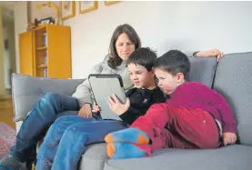  ?? Oli Scarff, Getty Images ?? A mother helps her sons navigate online learning resources provided by their school Tuesday in Marsden, England. Families across Great Britain and the world were coming to grips with home schooling and cabin fever.