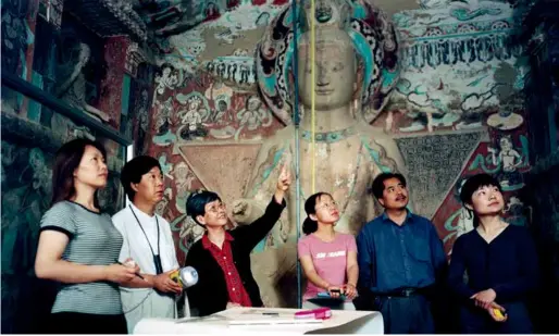  ?? 摄影 张伟文 ?? 2004年，时任敦煌研究院院长樊­锦诗（左三）在莫高窟第275窟指­导青年研究人员洞窟考­古调查工作。