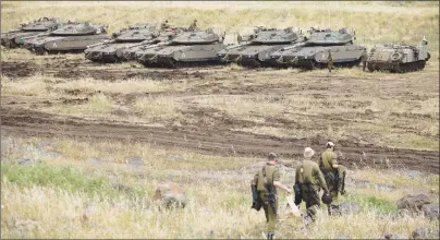  ?? AP PHOTO ?? Israeli soldiers walk past tanks in the Israeli-controlled Golan Heights, near the border with Syria Thursday. Israel says it struck dozens of Iranian targets in Syria overnight in response to a rocket barrage on Israeli positions in the Golan Heights....