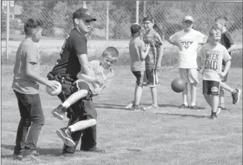  ?? Herald photo by Greg Bobinec ?? Officer Shawn Davis uses Rylen Baxter as a body shield to protect himself during a game of dodgeball at the AMA School Safety Patrol celebratio­n for kids showing leadership in safety at the crosswalk.