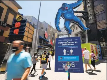  ?? Mark J. Terrill Associated Press ?? ECONOMISTS predict a slow economic recovery at tourist venues such as Universal CityWalk, where signs cautioned visitors to distance themselves from one another. The tourist attraction recently reopened.