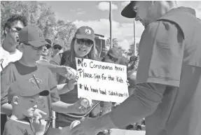  ?? SUE OGROCKI/AP ?? Angels reliever Taylor Cole hands a ball to Nash Theriault as brother Kaden waits his turn and mother Jeannine gives an “all clear” sign.