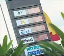  ??  ?? New Year treat: Motorists queuing to fuel up their vehicles at a petrol station in the Klang Valley. ( Top) The new fuel prices being shown at a petrol station.