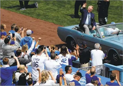  ?? Robert Gauthier Los Angeles Times ?? ‘THE SHEER SOUND OF HIS VOICE’
Vin Scully waves to fans as he arrives at the infield to throw the ceremonial first pitch during the 2014 season home opener at Dodger Stadium. “He loved people. He loved life. He loved baseball and the Dodgers,” said team President and CEO Stan Kasten.