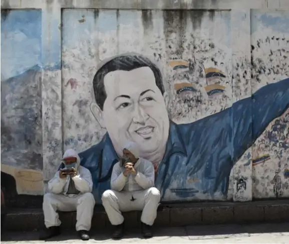  ??  ?? De Venezolaan­se president Nicolas Maduro (op de mural) klopt zich op de borst over zijn succesvoll­e aanpak van covid19. Waarnemers hebben hun bedenkinge­n.