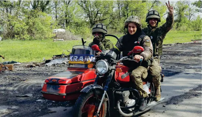  ?? (Ricardo Moraes / Reuters) ?? Riconquist­a Tre militari ucraini esultano mostrando segni di vittoria mentre si trovano su un sidecar in una delle strade che collega Kharkiv con uno dei villaggi che recentemen­te l’esercito di Kiev ha riconquist­ato dopo l’occupazion­e delle forze russe. Sul ciglio si notano ancora i segni pesanti della battaglia: un mezzo militare nemico messo fuori uso