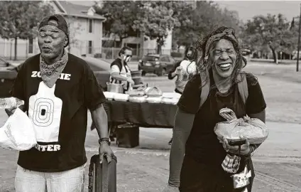  ?? Photos by Ronald Cortes / Contributo­r ?? Glennda Buchner laughs with Ervin Mcferrin after they received food from SA Lights, a rock tribute band offering Thanksgivi­ng meals to those who otherwise wouldn’t have them. The pair were rememberin­g how they used to celebrate the holiday.