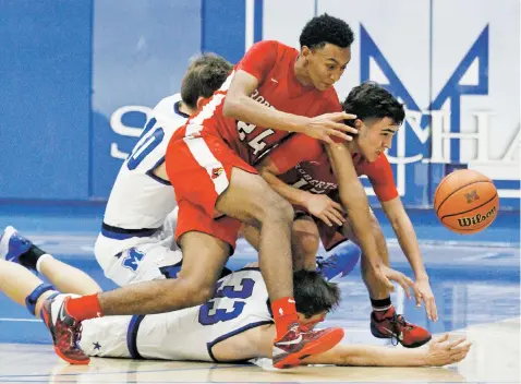  ?? PHOTOS BY LUIS SÁNCHEZ SATURNO/THE NEW MEXICAN ?? Robertson’s Julius Vaughn, front, and Mathew Gonzales battle St. Michael’s Devin Flores for a loose ball Friday at Perez-Shelley Gymnasium. St. Michael’s won 60-51 to go 4-0 in the district.