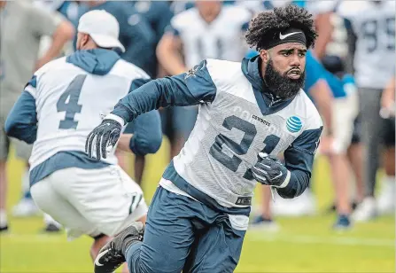  ?? ASSOCIATED PRESS FILE PHOTO ?? Ezekiel Elliott runs by teammate quarterbac­k Dak Prescott (4) after faking the handoff during the Cowboys’ training camp July 26 in Oxnard, Calif.