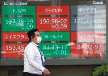  ?? — Reuters ?? A man walks past an electric monitor displaying the Japanese yen exchange rate against the US dollar in Tokyo.
