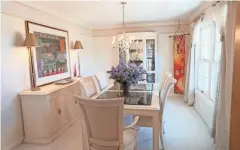  ??  ?? The formal dining room features white carpet and cream-colored furniture, including a table with a smoky glass top.