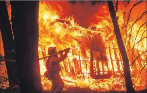  ?? AP PHOTO ?? Firefighte­r Jose Corona sprays water as flames consume a home in Magalia, Calif., on Friday.