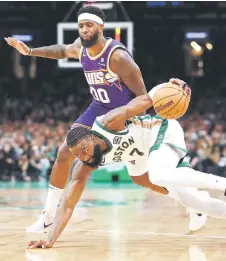  ?? — AFP photo ?? Jaylen Brown of the Boston Celtics recovers with the ball after tripping ahead of Royce O’Neale of the Phoenix Suns .