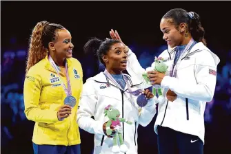  ?? Naomi Baker/Getty Images ?? Gold medalist Simone Biles, center, shares the stage with silver medalist Rebeca Andrade of Brazil, left, and bronze medalist Shilese Jones, her U.S. teammate.