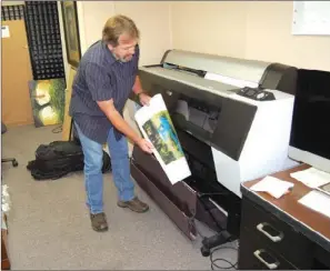  ?? WAYNE BRYAN/TRILAKES EDITION ?? A commercial printer and well-known nature and wildlife photograph­er, Taylor Bellott catches a new print of his work at his art gallery in downtown Hot Springs. Bellott also produces prints for other artists and is working on printing a book for one of...
