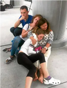  ?? —AP ?? People take cover behind a post at Fort Lauderdale-Hollywood Internatio­nal Airport after a gunman, an Iraq war veteran, opened fire and killed at least five people.