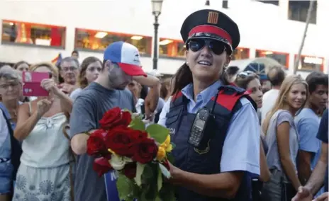  ?? MANU FERNANDEZ/THE ASSOCIATED PRESS ?? A police officer holds roses given to her by peace demonstrat­ors during a massive march Saturday. An estimated half a million people took to the streets.