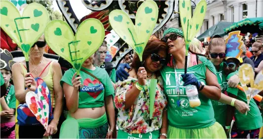  ??  ?? Respectful: Carnival-goers wearing green, as organisers had requested, observe a minute’s silence for the fire’s victims