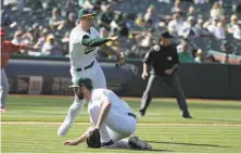  ?? Jeff Chiu / Associated Press ?? First baseman Matt Olson makes an off-target throw to first, an error that allowed the Angels to take the lead in the 11th.