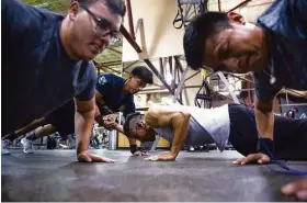  ??  ?? Erik Cuevas, back left, helps Alex Aburto do a one-arm push-up as Jonathan Hernandez, front left, and Victor Aburto do individual push-ups during a latenight workout session at 24 Hour Fitness.