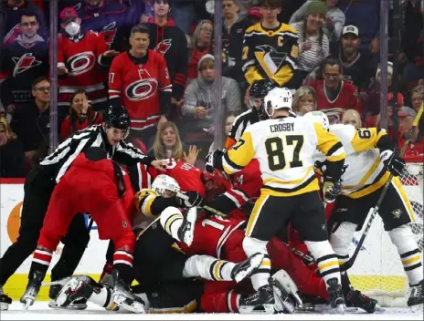  ?? Jared C. Tilton/Getty Images photos ?? Officials attempt to sort out a pileup in the second period of the game between the Penguins and Hurricanes in Raleigh, N.C.