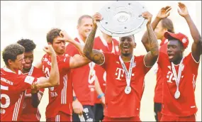  ?? Kai Pfaffenbac­h / Associated Press ?? Munich’s Jerome Boateng lifts the trophy after the German Bundesliga soccer match between VfL Wolfsburg and FC Bayern Munich on Saturday in Wolfsburg, Germany.