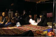  ?? ?? Iraqi campers play backgammon as others smoke a water pipe inside his tent in the Samawa desert south of Baghdad.