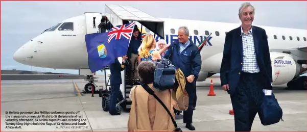  ??  ?? St Helena governor Lisa Phillips welcomes guests off the inaugural commercial flight to St Helena island last Saturday afternoon, as Airlink captains Jaco Henning and Tammy King (right) hold the flags of St Helena and South Africa aloft.