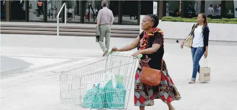  ??  ?? A woman shopper pushes her trolley at an upmarket shopping mall in Sandton, Johannesbu­rg.