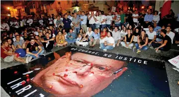  ?? Reuters photo ?? Protesters throw tomatoes and coins on a banner calling on Malta Police Commission­er Lawrence Cutajar to resign, while blocking the road outside the Malta Police headquarte­rs during a protest over the assassinat­ion of Galizia.—