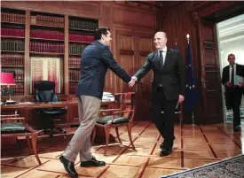  ?? —AFP ?? ATHENS: European Economic and Financial Affairs Commission­er Pierre Moscovici (R) shakes hands with Greek Prime Minister Alexis Tsipras (L) during a meeting at the Maximou mansion.