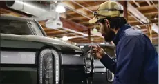  ?? ANDY CROSS — THE DENVER POST ?? Rivian field service technician Mark Rivera checks the cover on the charging port on a Rivian R1T electric truck at the Rivian Service Center on Feb. 8.