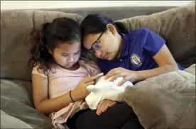  ?? Jennifer Sinco Kelleher / AP photo ?? Fiamaua Cecilia Purdy (left) and her sister Sina Marie Purdy watch on a phone in their home in Kapolei on Dec. 14. The family moved to Las Vegas in 2017 to escape Hawaii's high cost of living and returned last year and share two bedrooms in a home they rent with extended family. Native Hawaiians, like the Purdys, who have been priced out of Hawaii are finding more affordable places to live in cities like Las Vegas.