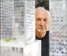  ?? ERIK CARTER / THE NEW YORK TIMES ?? Frank Gehry looks out from behind a model of the King Street project designed for his native Toronto, April 6 at his architectu­re studio in Los Angeles. At 92, the Pritzker-winning architect is focusing on social justice projects and dismisses the idea of scaling back. “What would I do?” he said. “I enjoy this stuff.”