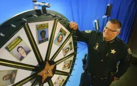  ?? Malcolm Denemark, Florida Today ?? Brevard County Sheriff Wayne Ivey gets ready to spin his popular “Wheel of Fugitive” in Titusville, Fla. The popular videos feature photos of 10 of the county’s most wanted criminals.