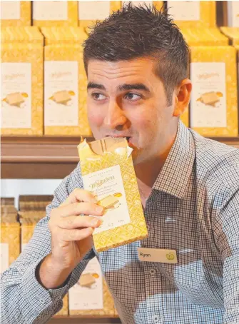  ?? Picture: GLENN HAMPSON ?? Woolworths Coomera West assistant store manager Ryan O'Neill tries out the Whittaker’s buttermilk chocolate which is proving a hit with Cadbury Caramilk fans.