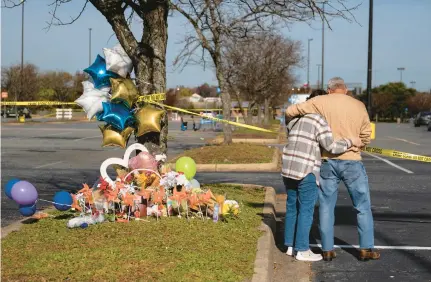  ?? BILLY SCHUERMAN/STAFF ?? Debbie, left, and Chet Barnett place flowers at a memorial outside of the Chesapeake, Virginia Walmart on Nov. 24 where six were killed earlier in the week. The Barnetts have lived in Chesapeake for almost 40 years.