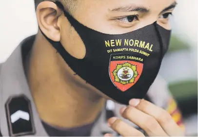  ?? Picture: EPA-EFE ?? A police officer wears a mask featuring the words ‘new normal’ yesterday, while waiting for his turn during a Covid-19 swab test in Medan, North Sumatra, Indonesia. The government has imposed regulation­s, known as ‘New Normal’, which will be implemente­d in stages.